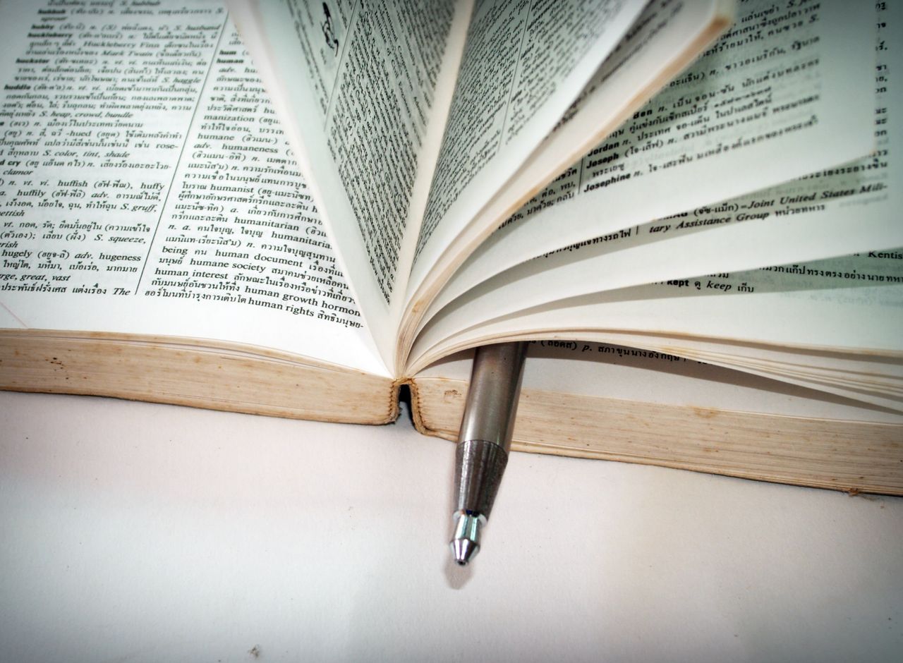about-us-02 A close-up of an open dictionary with a pen separating the pages for convenient reference.