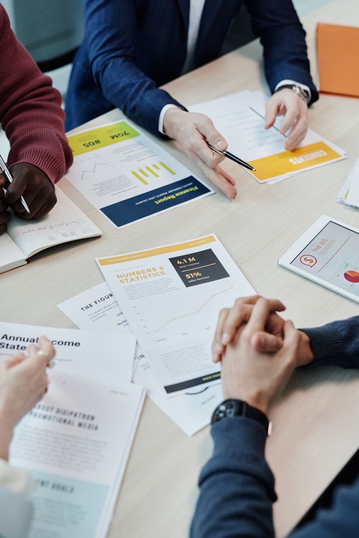 Team members discuss data reports and statistics in a collaborative setting around a table.